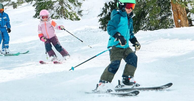 A group of children skiing down a snowy slope, enjoying a winter day in a mountainous landscape.