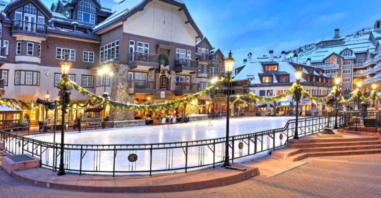 A festive ice rink located in front of a building, beautifully decorated with twinkling Christmas lights for the holiday season.
