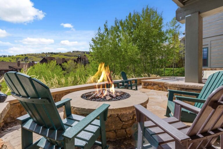 two adirondack chairs in front of a firepit